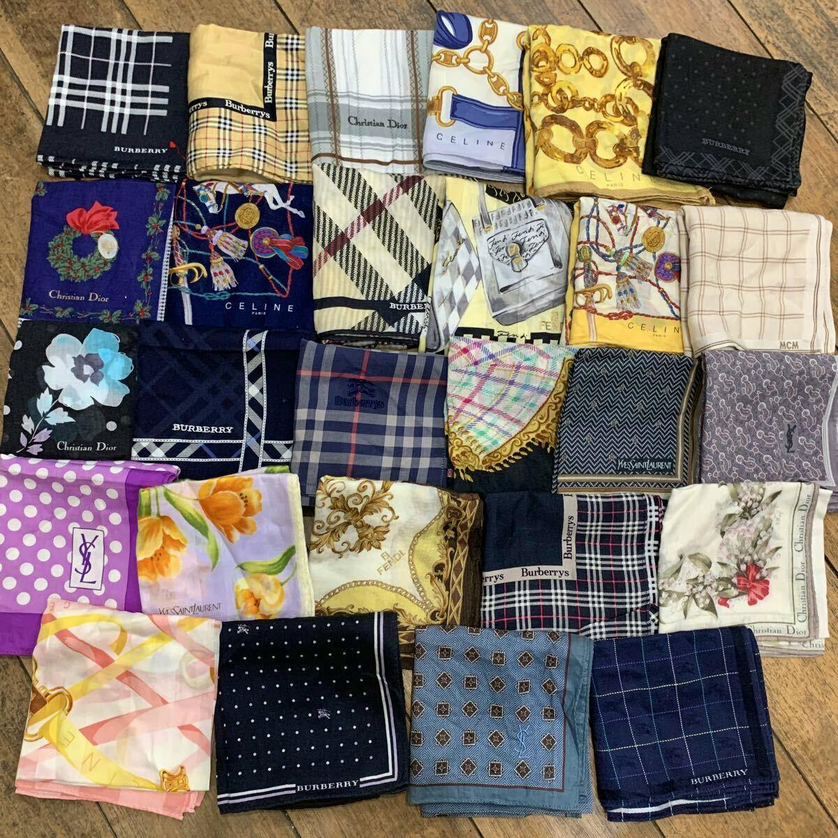 Multiple folded branded handkerchiefs (silk scarves) arranged in a grid on a wooden floor, showing various patterns and logos.