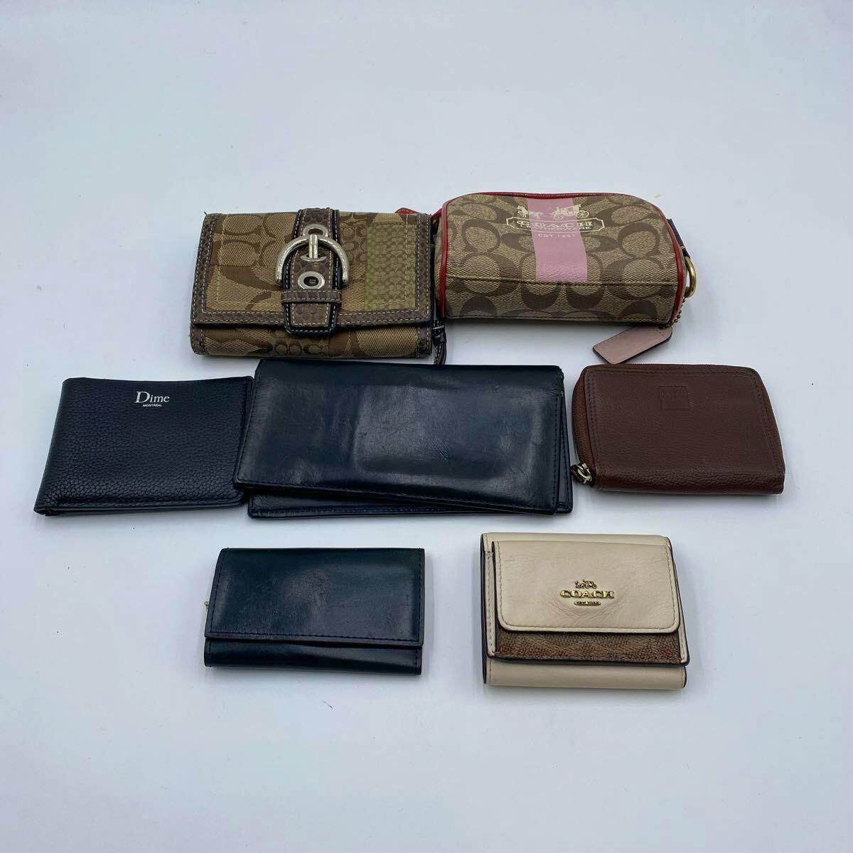 A collection of wallets and small pouches, including several leather wallets and patterned pouches, arranged on a white background.