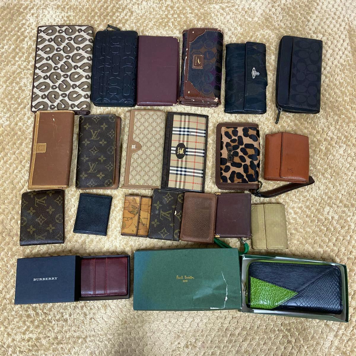 Multiple men's and women's wallets, card cases, key cases, and coin cases arranged on a carpeted floor.