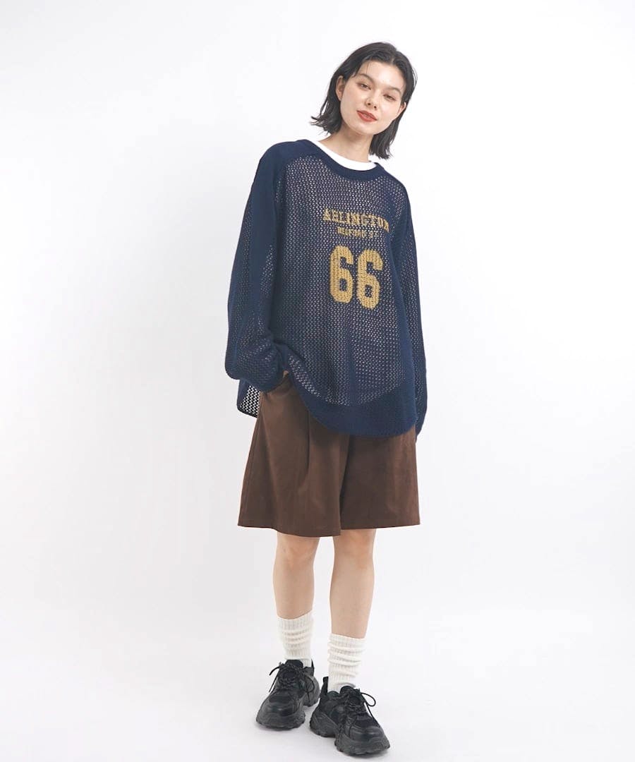 A model wearing brown women’s shorts with a navy mesh top, white socks, and black sneakers against a white background.