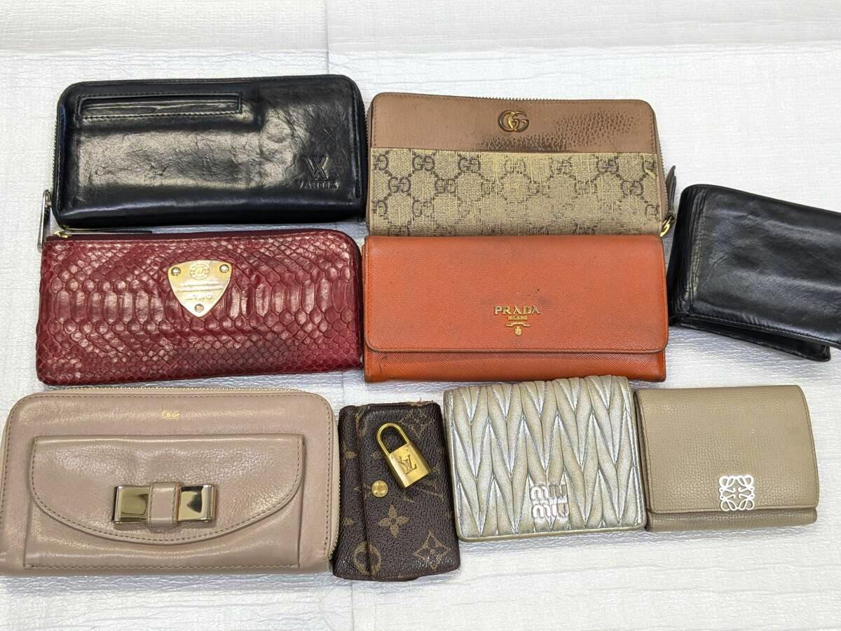 Multiple wallets and key cases, including an orange Prada wallet, displayed on a white background.
