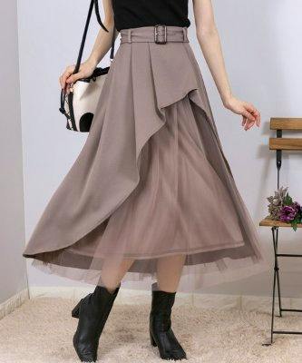 Model wearing an asymmetrical women's skirt with visible tulle layers, shown mid-calf length.