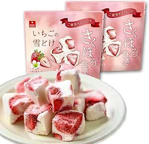 Two pink bags of Aszak Foods Strawberry Snowflake freeze-dried chocolate covered strawberries with a plate of bite-sized strawberry pieces in front.