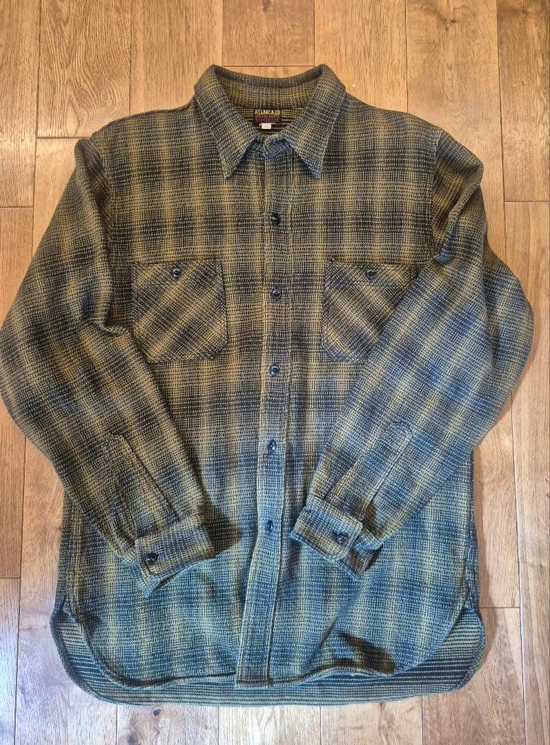 Front view of the men's cotton checkered button-up shirt laid flat on a wooden floor.