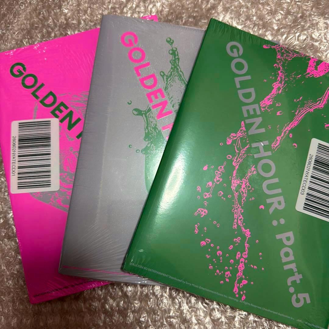 Three sealed ATEEZ "GOLDEN HOUR: Part.5" CD packages in pink, silver, and green covers arranged on bubble wrap.
