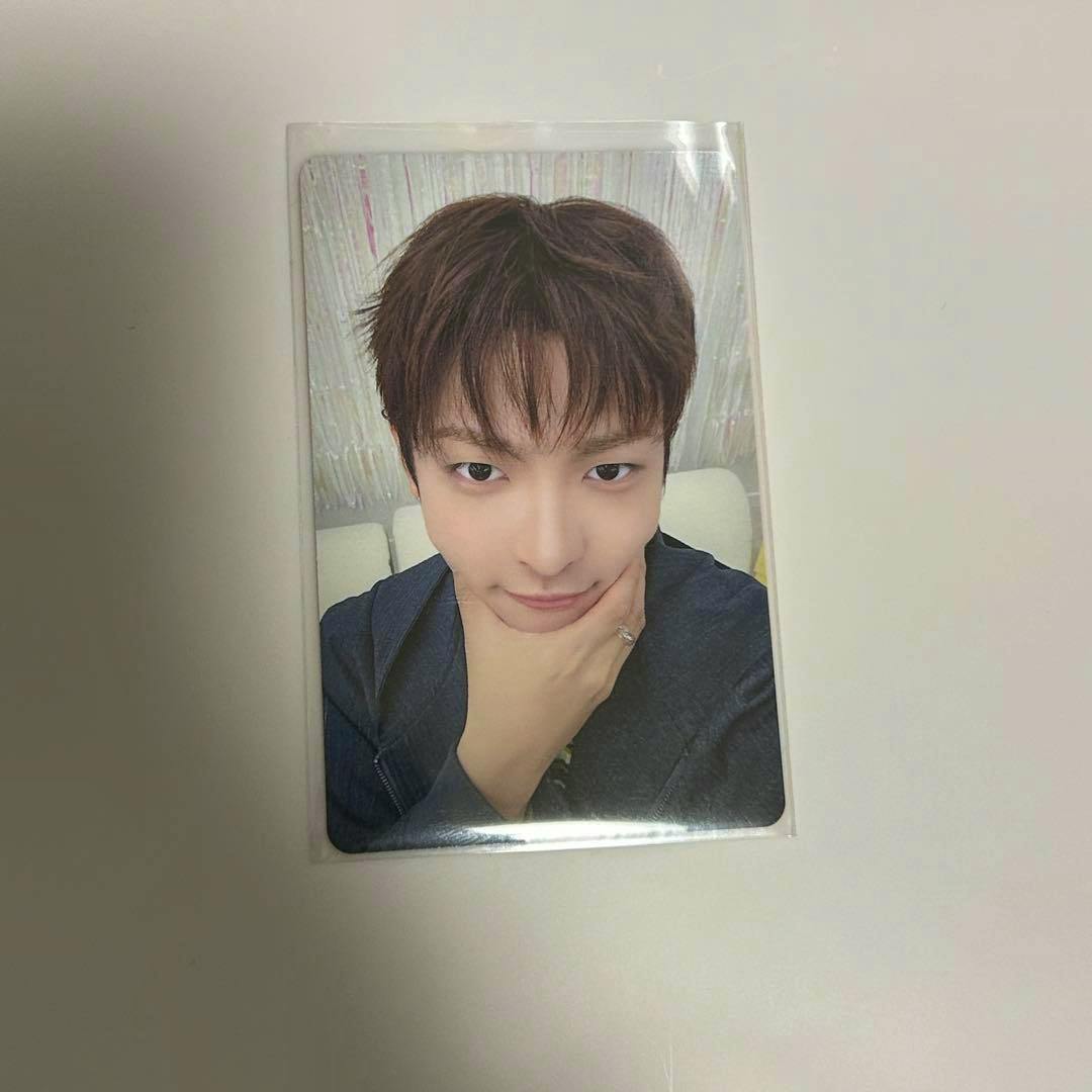 Glossy rectangular photocard inside a clear plastic sleeve on a white surface.