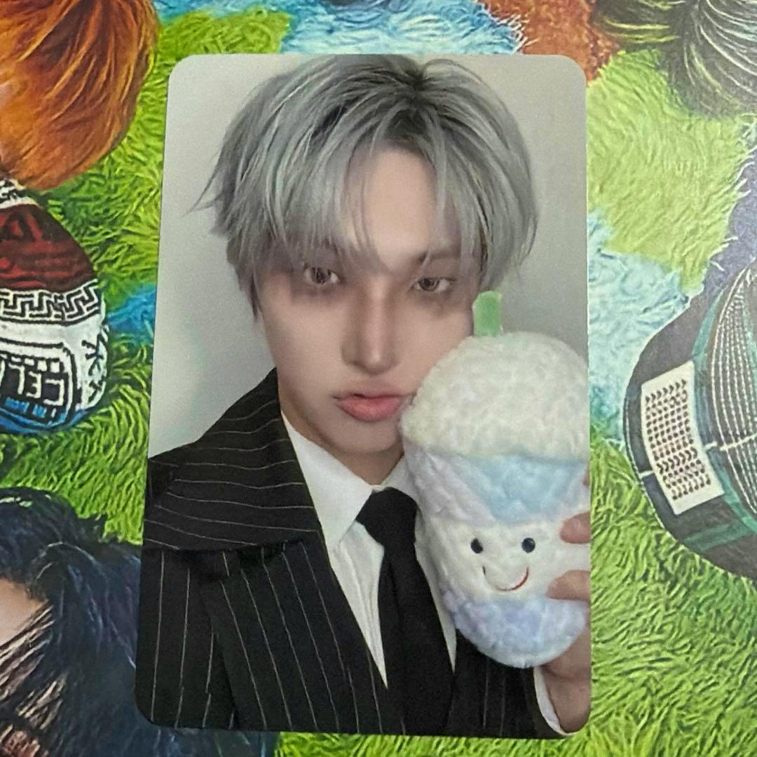 Photocard front showing a person in a pinstripe suit holding a plush milk-tea cup.