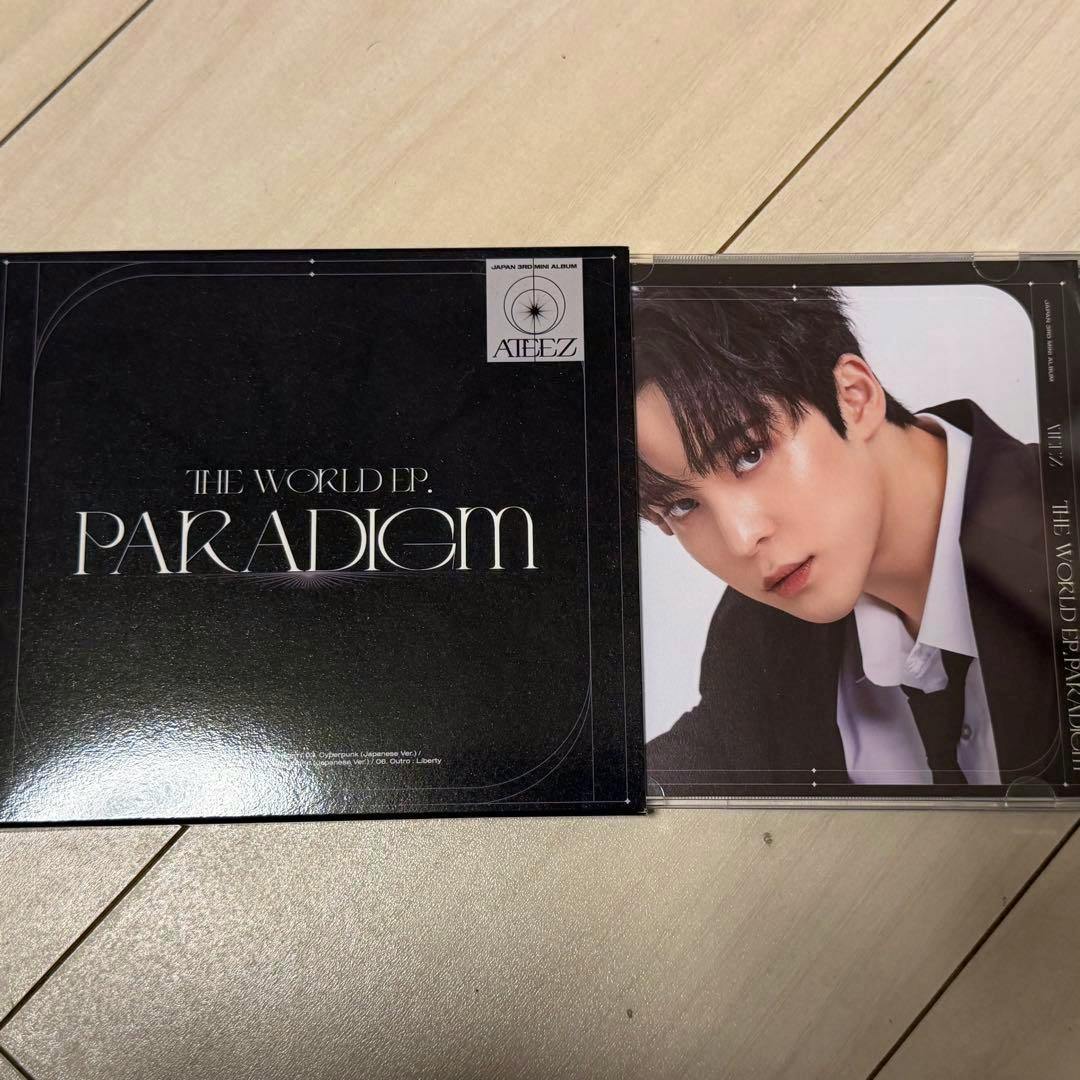 Photograph of the ATEEZ PARADIGM CD case showing the black album cover and a portrait photo insert of a member.