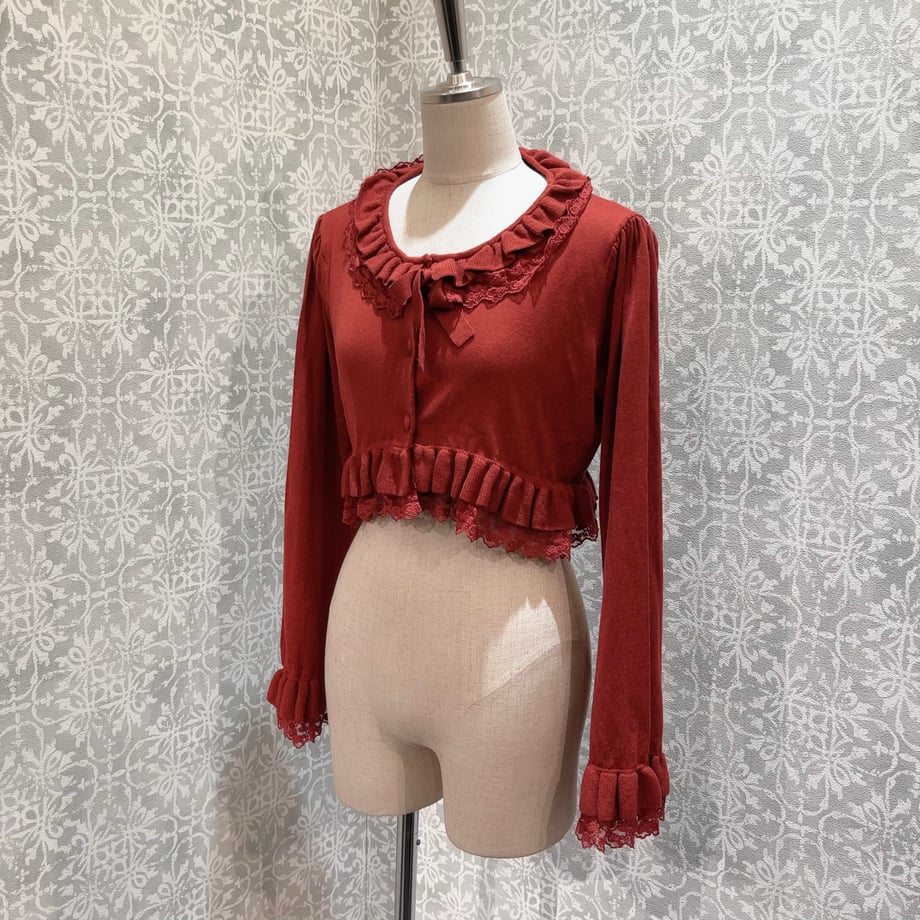 Red Rose Waltz cardigan displayed on a mannequin against a patterned backdrop.
