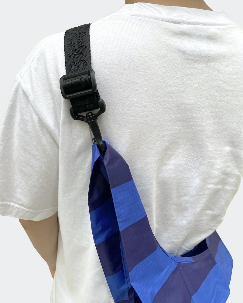 Close-up of the attachable strap clipped to a blue and purple striped bag worn over a person's shoulder.