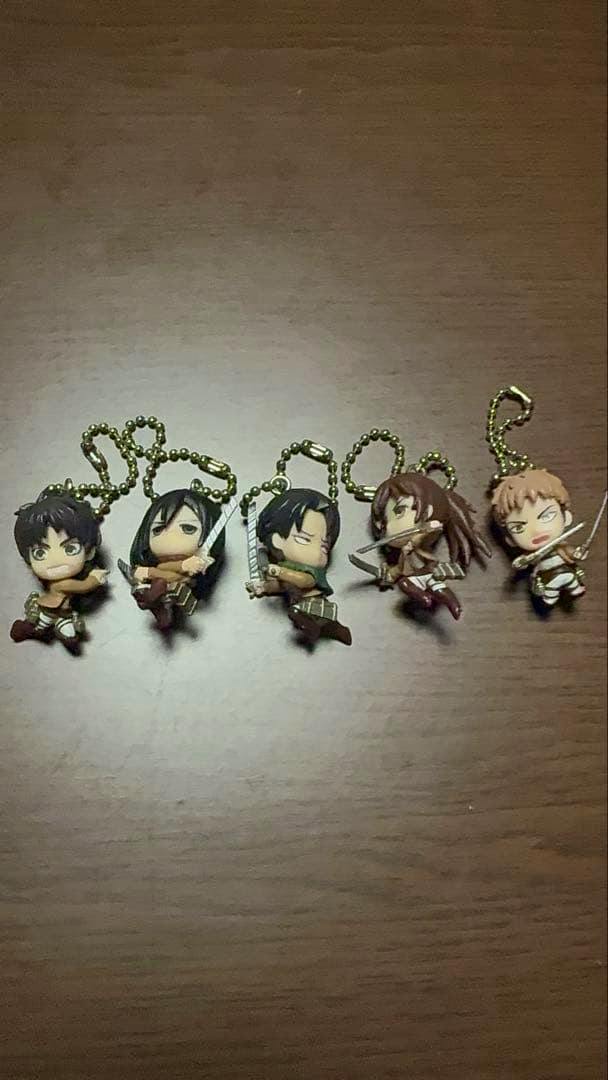 Five chibi Attack on Titan ball-chain mascot figures arranged on a wooden surface.