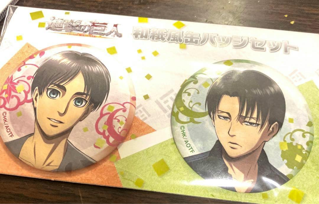 Packaged set of two round Attack on Titan can badges showing Eren on the left and Levi on the right.