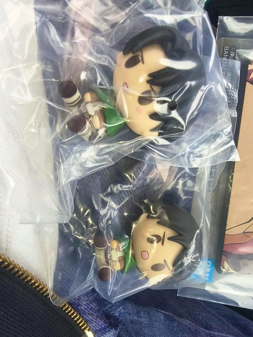 Two small plastic Attack on Titan chibi figures (H prize) sealed in clear bags lying on fabric.