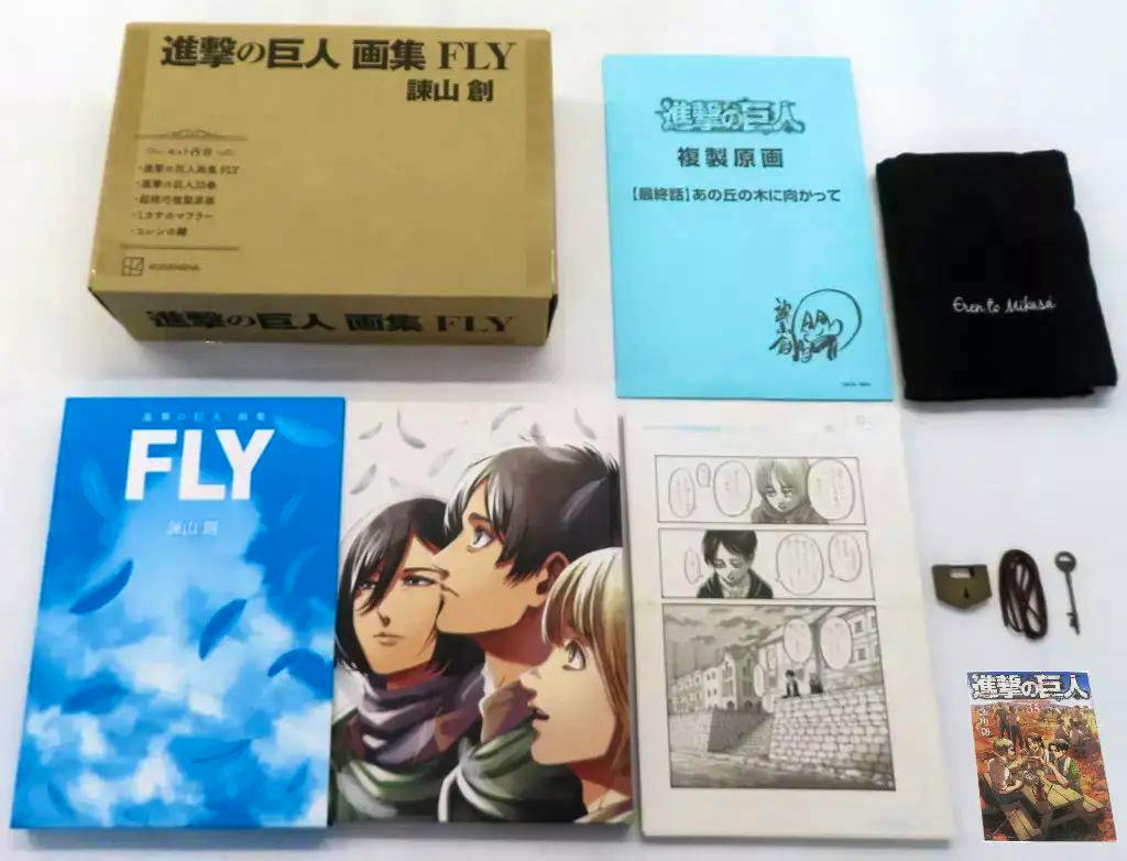Photograph of the 進撃の巨人 画集 FLY illustration book with its box, inserts, and accessories arranged on a white background.