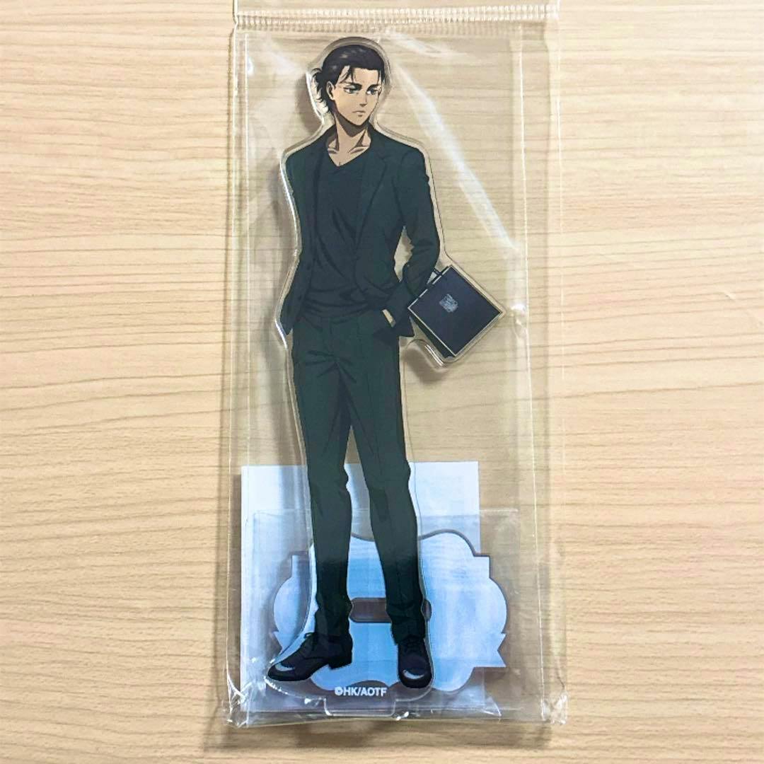 Packaged acrylic decorative stand of Eren from Attack on Titan in a clear plastic sleeve on a light wood surface.