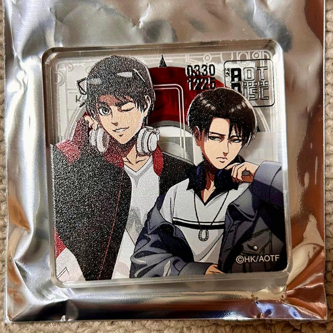 Square acrylic block showing printed artwork of Eren and Levi from Attack on Titan, displayed inside silver foil packaging.