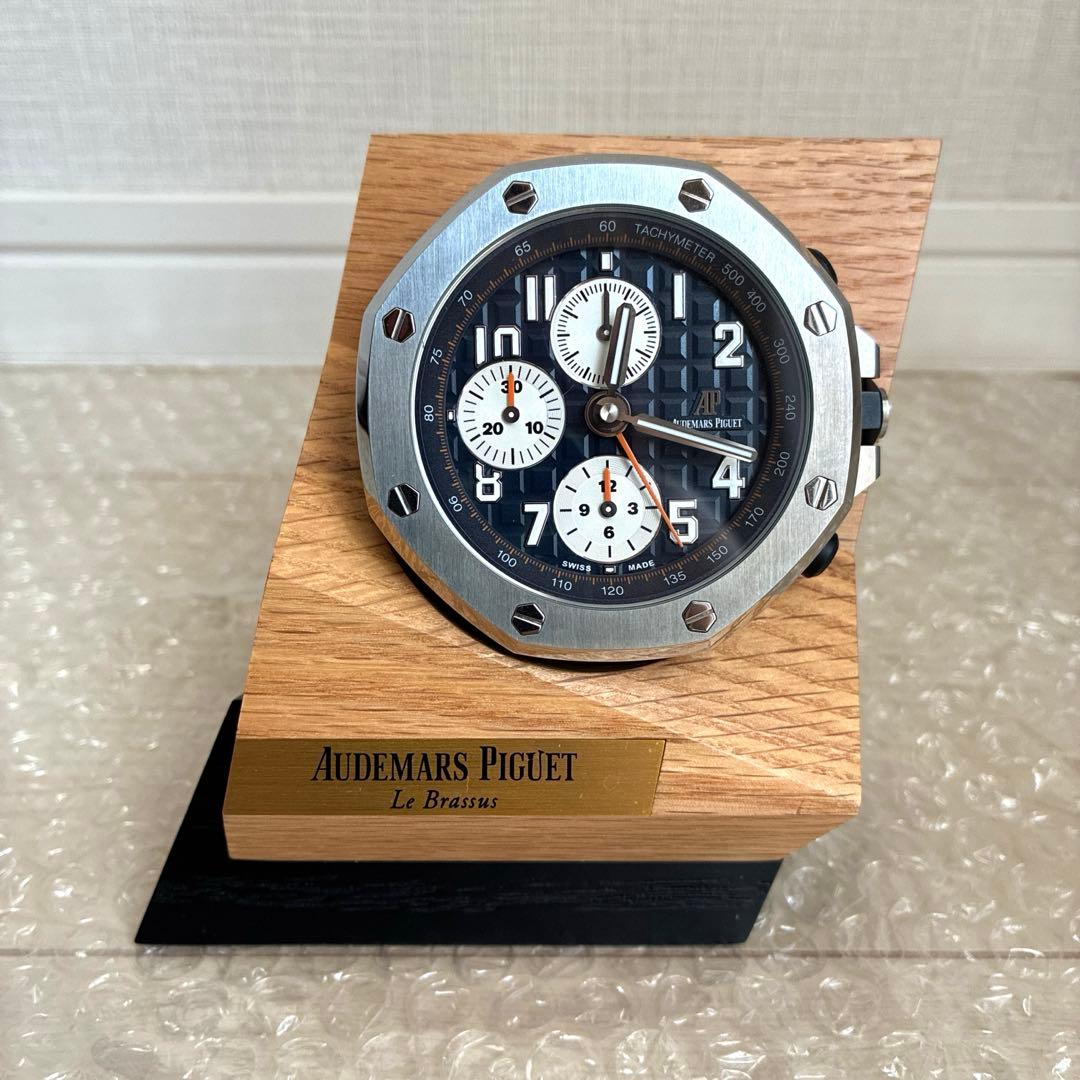 Front view of an Audemars Piguet Royal Oak Offshore table clock mounted on a wooden angled stand with a brass Audemars Piguet nameplate.