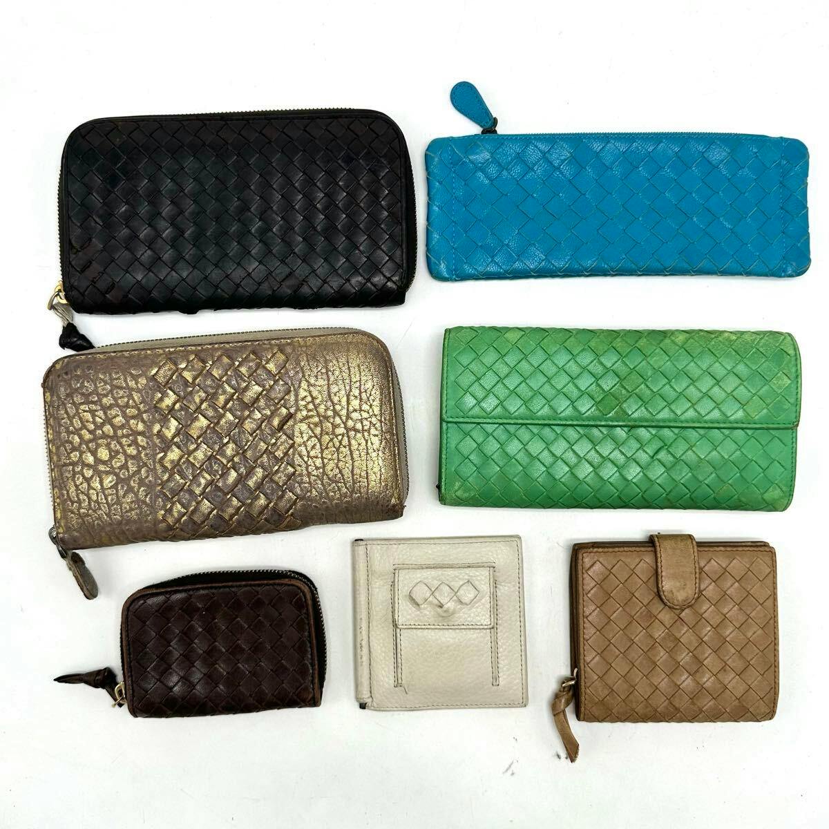 Seven Bottega Veneta woven leather wallets and small cases in various colors arranged on a white background.