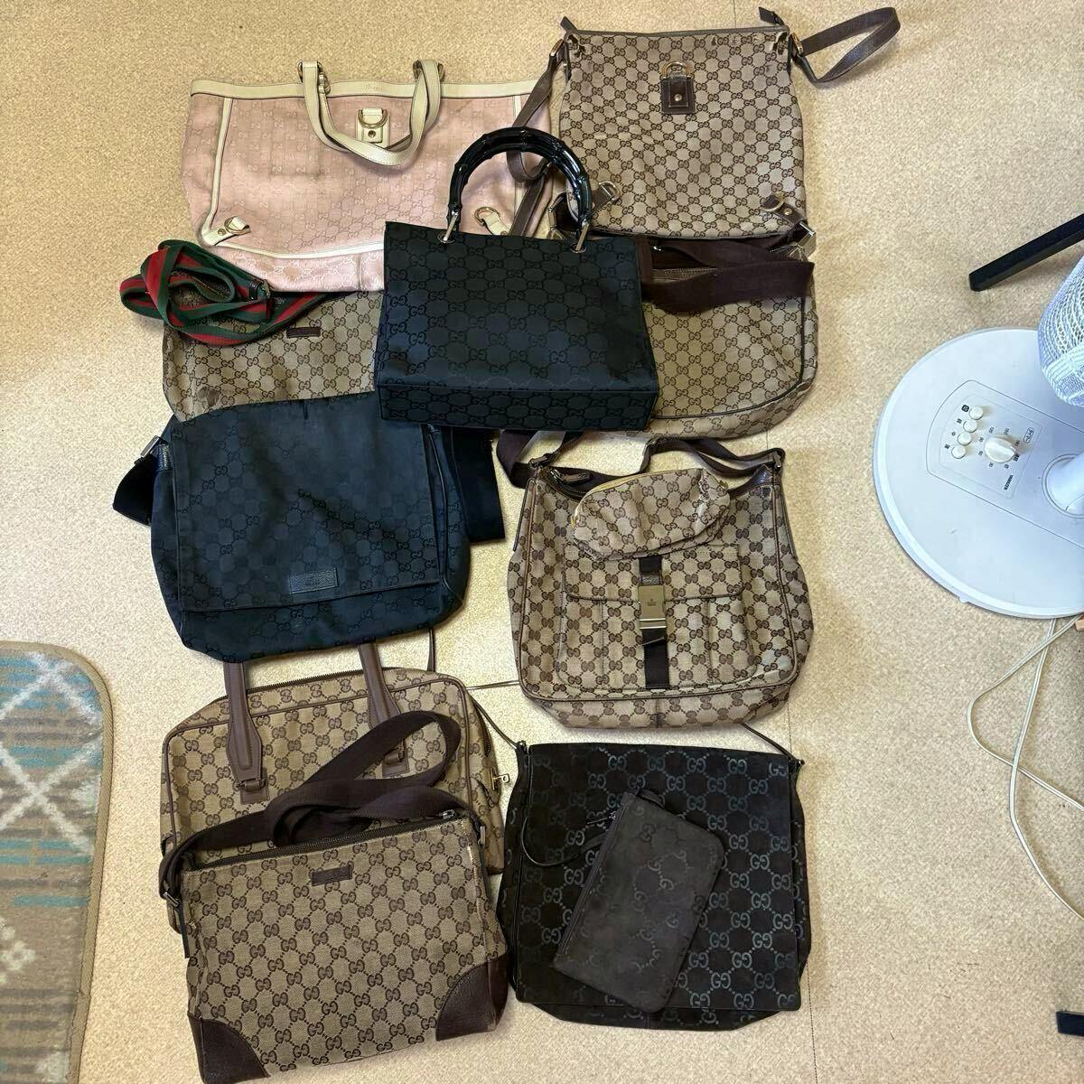 Multiple GUCCI GG canvas bags, pouches, and straps arranged on a floor as a bulk set.