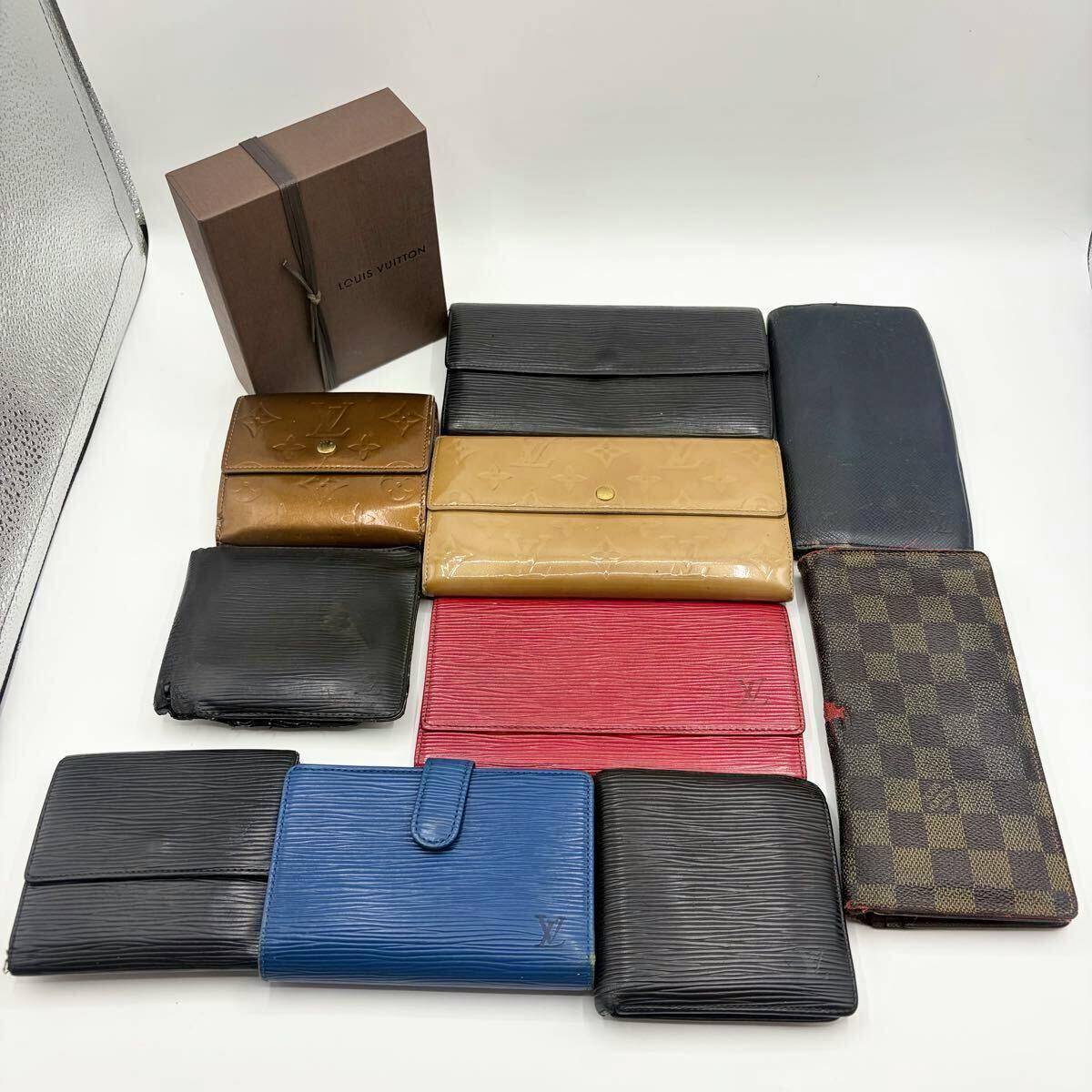 Ten Louis Vuitton wallets and a Louis Vuitton box arranged on a white background.