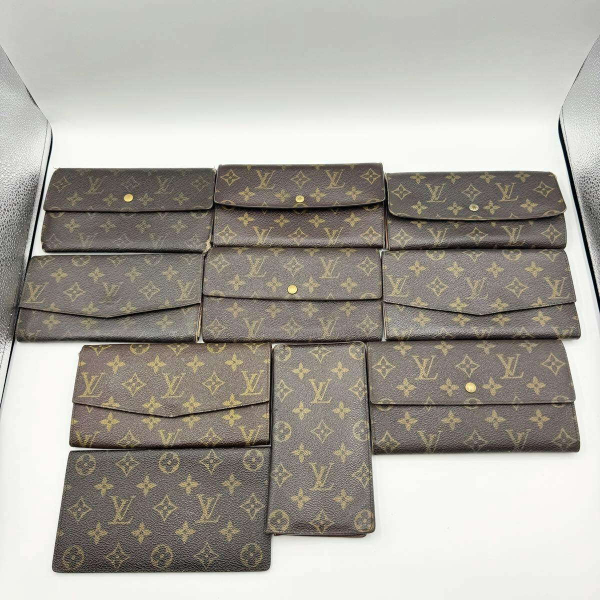 Ten Louis Vuitton monogram wallets arranged on a white background, showing various flap styles and wear.