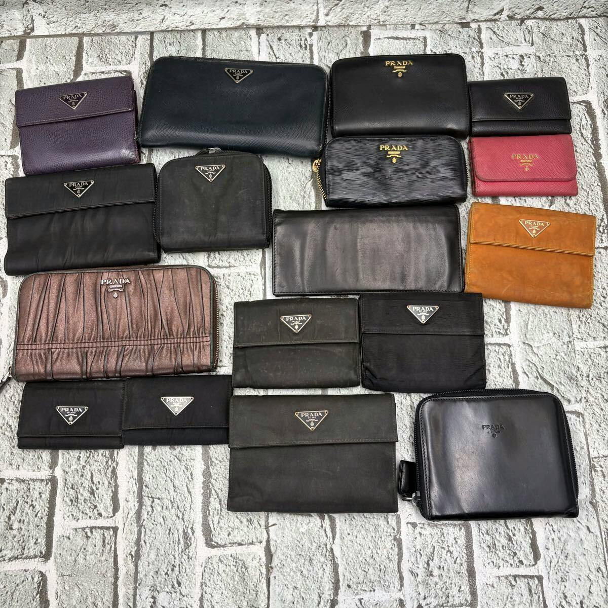 Multiple PRADA wallets and small wallets arranged on a light brick-patterned surface, showing different styles and logos.