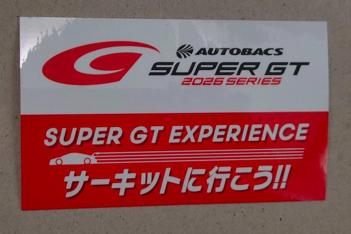 A paper sticker showing the AUTOBACS SUPER GT 2026 SERIES logo above a red panel reading “SUPER GT EXPERIENCE” and Japanese text.