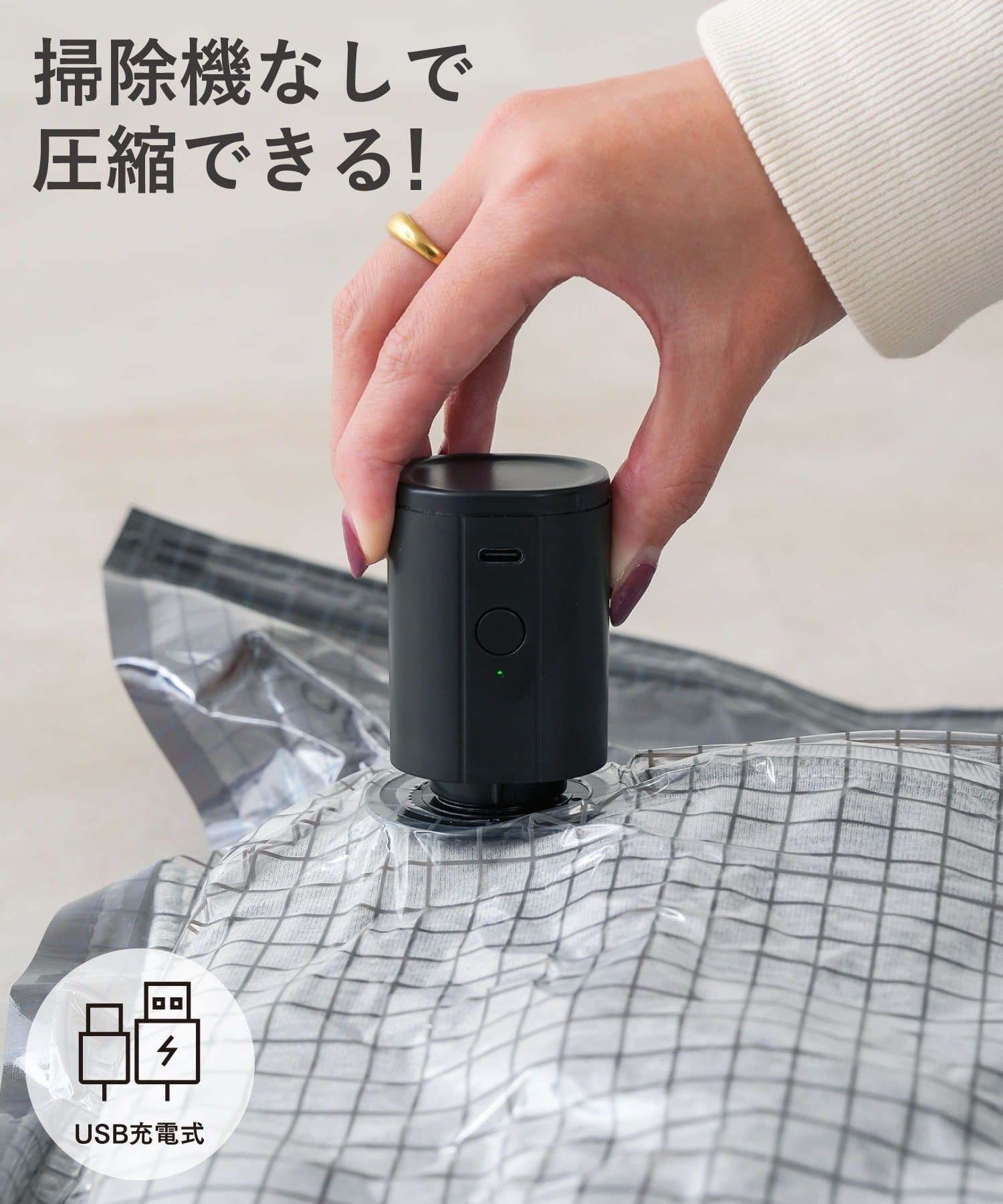 A small black automatic vacuum compressor placed on a vacuum storage bag being pressed by a hand.