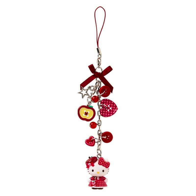 Red phone strap showing a dangling apple-themed Hello Kitty rubber charm and multiple red decorative charms.