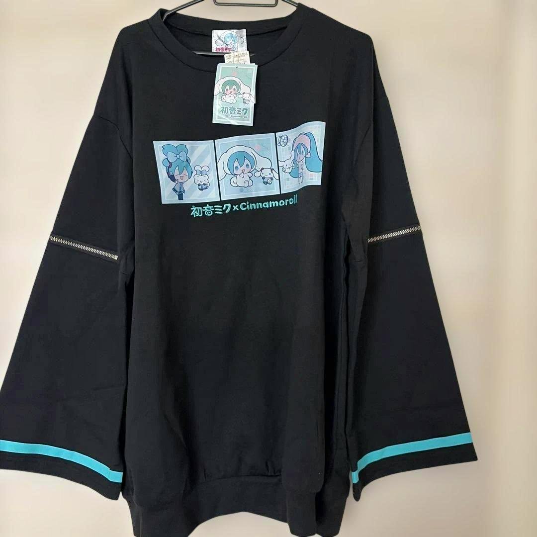 Black long-sleeve sweatshirt hanging on a hanger with a three-panel mint-green 初音ミク×Cinnamoroll graphic on the chest and mint-green trim on the sleeves.