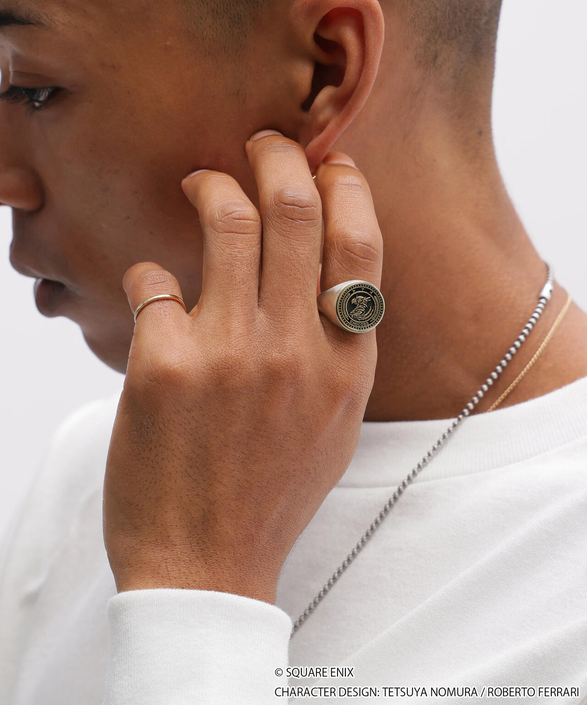 Model shown in profile wearing the AVIREX × FINAL FANTASY VII REMAKE silver signet ring (Chocobo) on their finger.