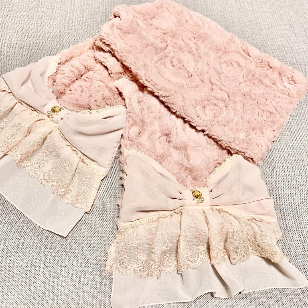 Light pink faux-fur muffler scarf with large decorative bows and lace trim laid flat.