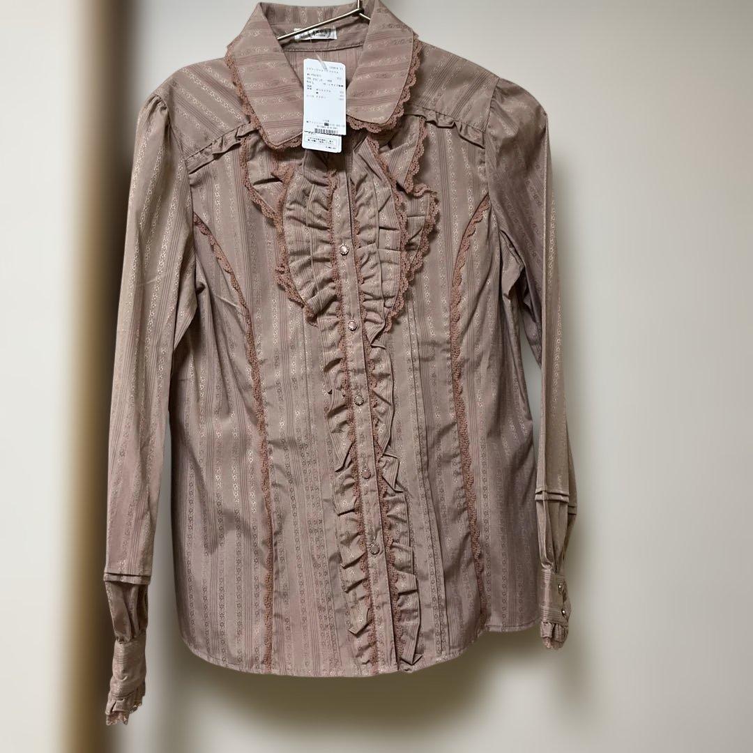 Front view of an axes femme pink floral jacquard women's blouse with a tag attached to the collar.