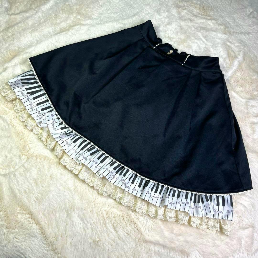 Black kids' skirt with a piano-key printed ruffle and lace trim laid flat on a soft background.