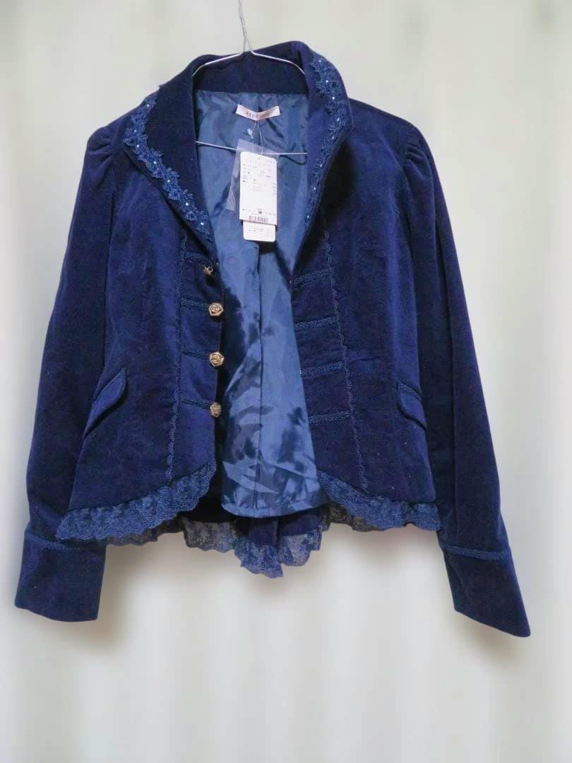 Front view of a navy women's jacket with frilled hem and decorative buttons hanging on a hanger.