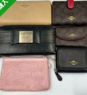 Six assorted wallets and pouches, including Coach and Michael Kors styles, arranged on a flat surface.