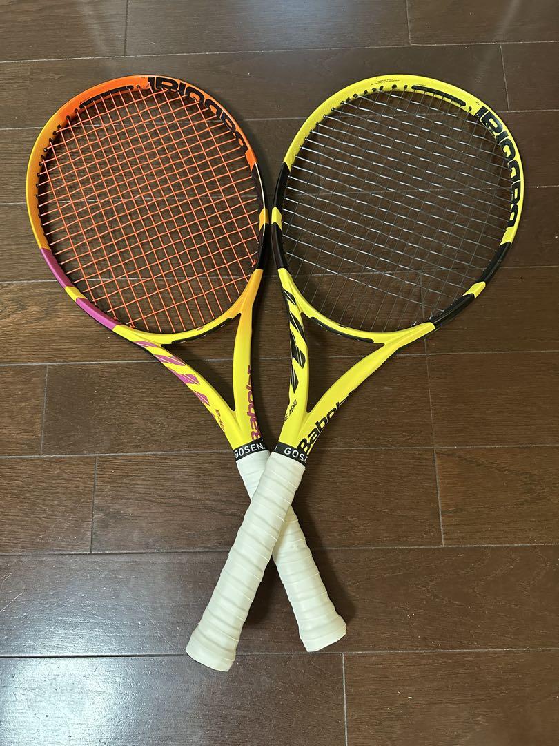 Two Babolat Pure Aero tennis rackets crossed on a wooden floor.