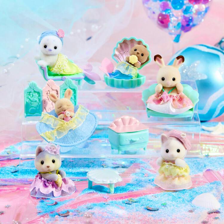 Mermaid-themed baby figure parts and small plastic furniture pieces arranged on a pastel display.