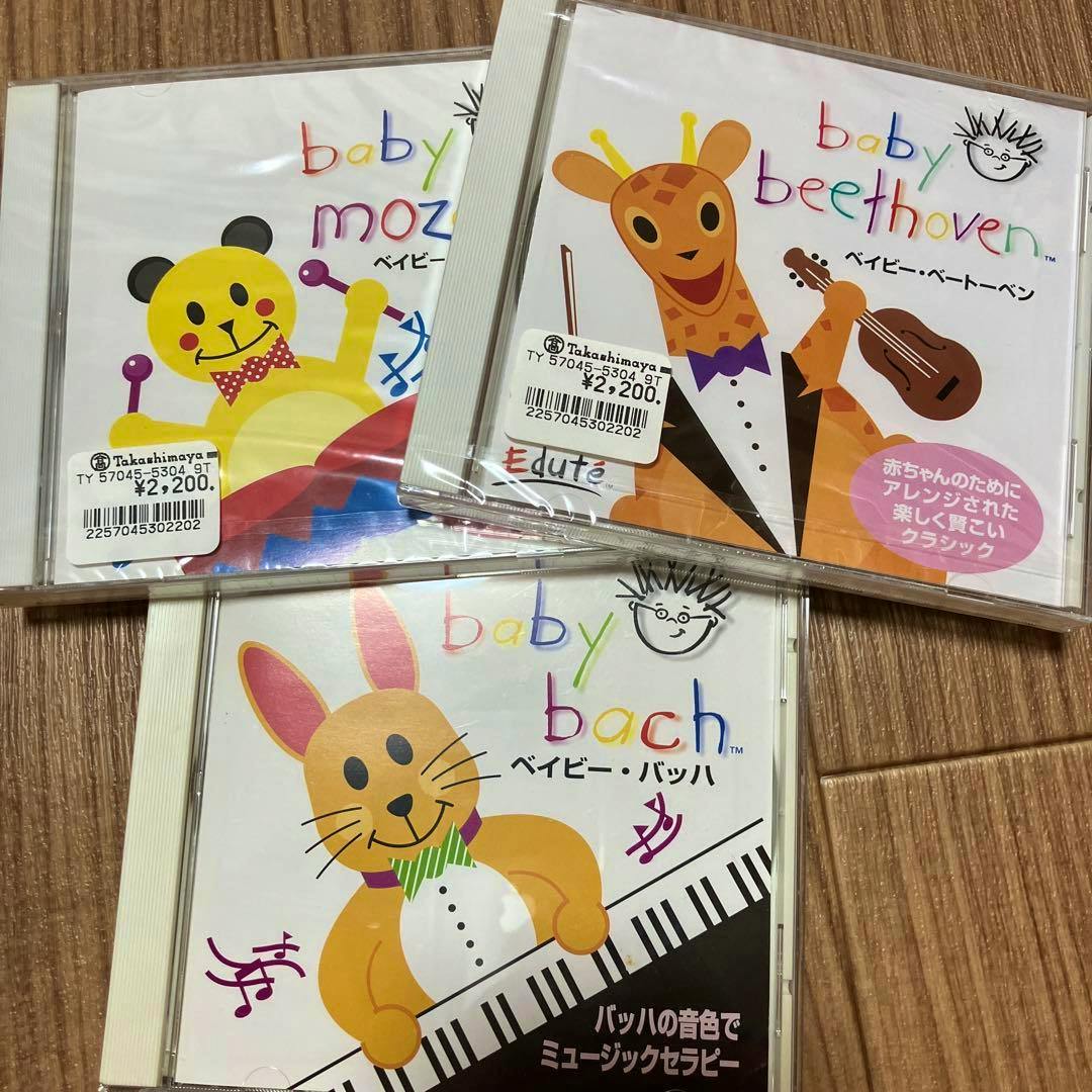 Three Baby classical CD jewel cases (Baby Mozart, Baby Beethoven, Baby Bach) showing illustrated covers and price stickers on a wood surface.