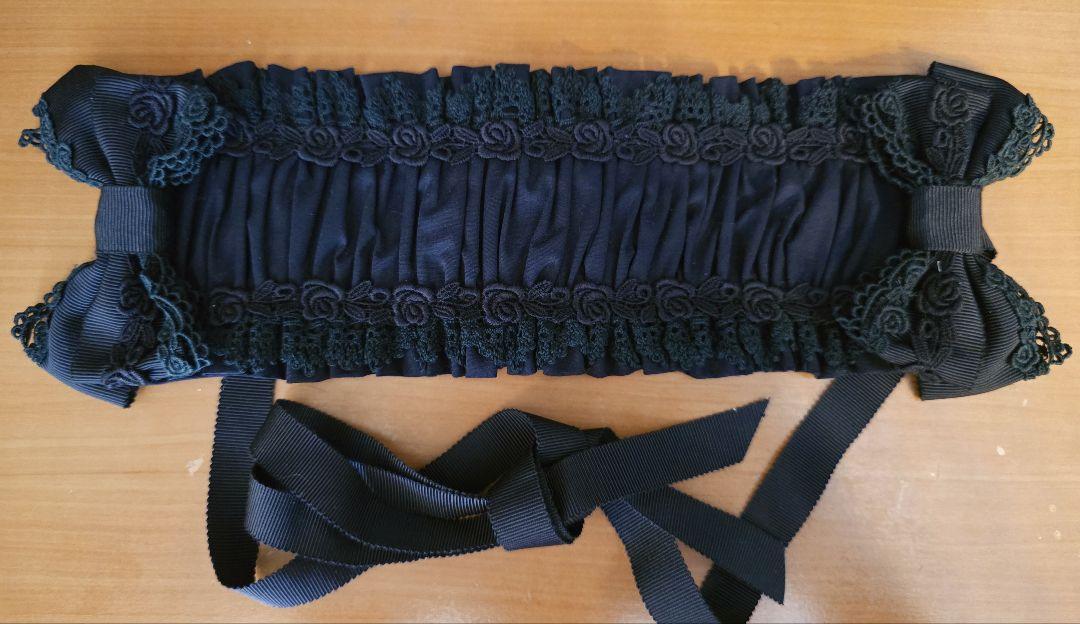 Black BABY,THE STARS SHINE BRIGHT headdress with gathered fabric and ribbon ties laid flat on a wooden surface.
