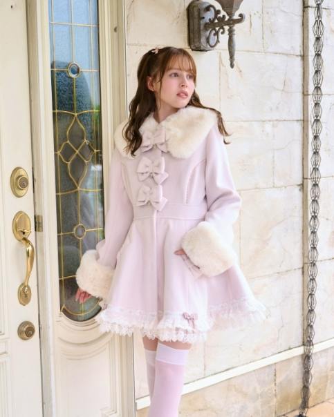 Model wearing a light pink women's tiered ribbon coat with faux-fur collar and cuffs, front bows, and a lace-trimmed hem.
