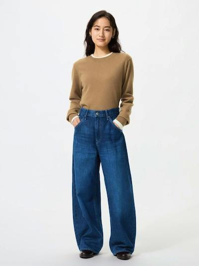 Model wearing blue baggy barrel-leg jeans standing full-length facing forward.