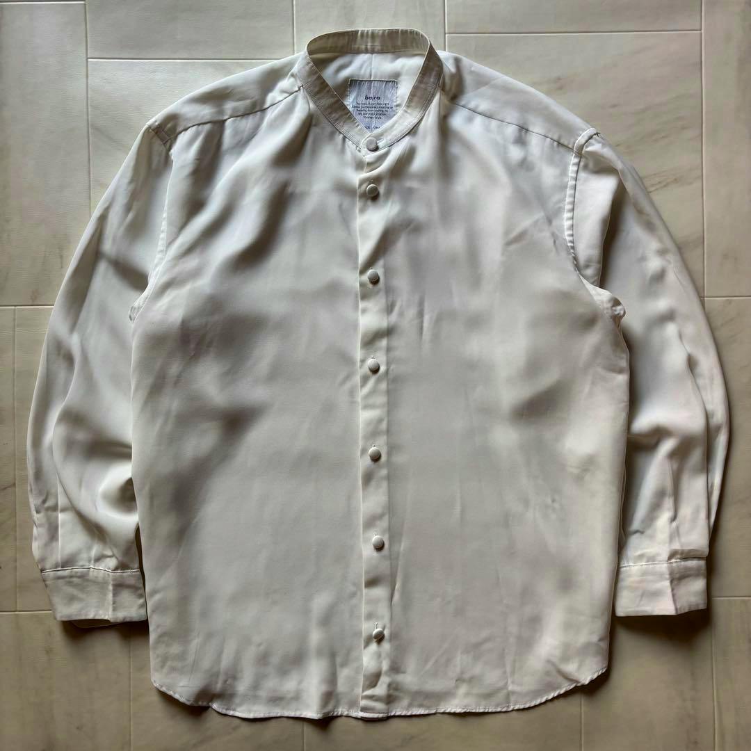 White stand-collar men's long-sleeve shirt laid flat showing front buttons and cuffs.