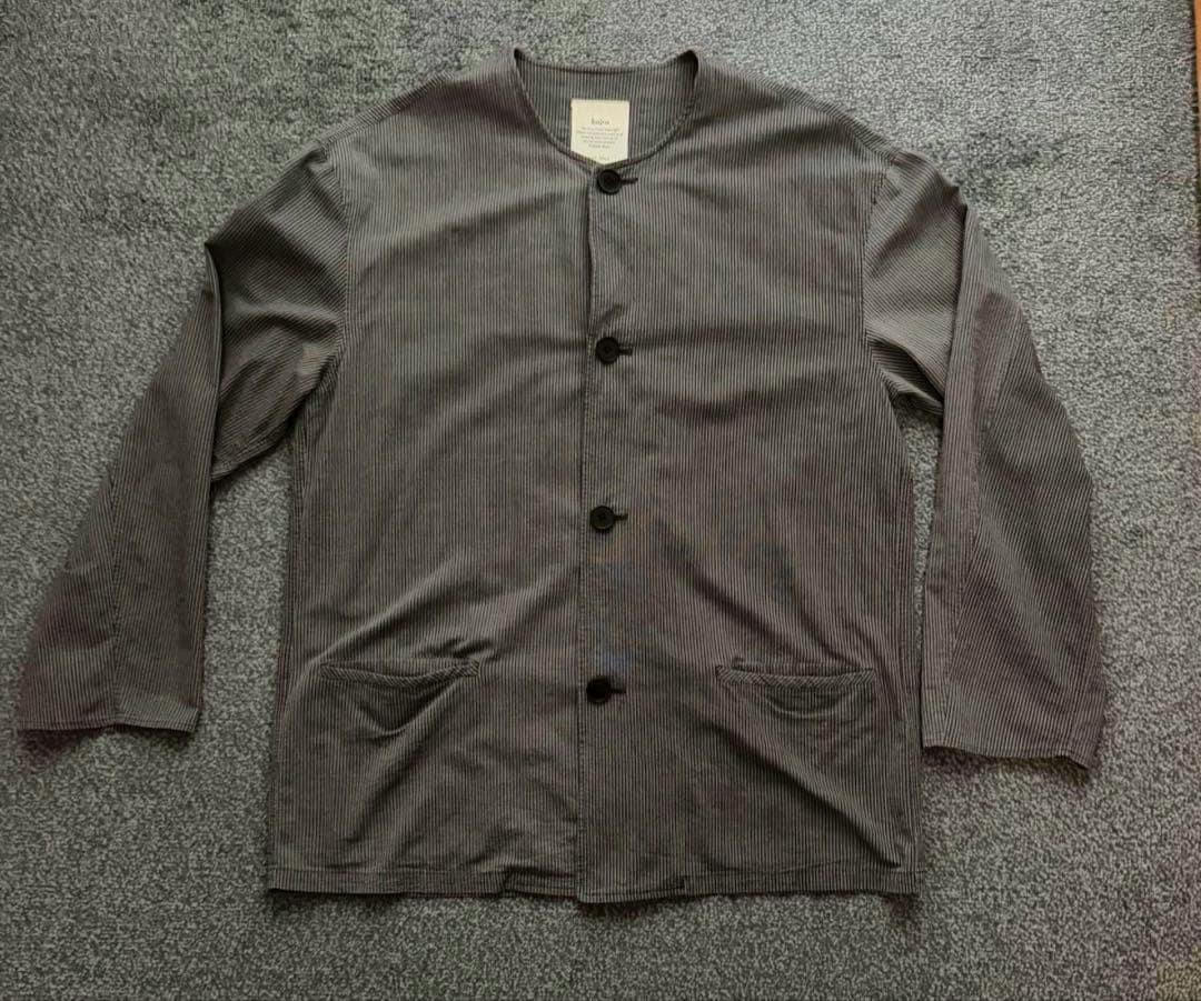 Front view of the bajra striped no-collar jacket laid flat on carpet, showing buttons and front pockets.