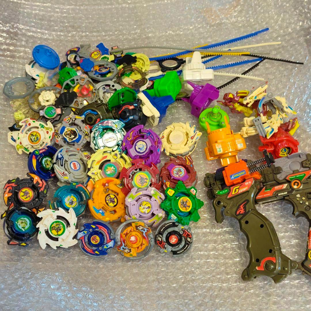 A pile of Beyblade tops, launchers, and ripcords arranged on bubble wrap.
