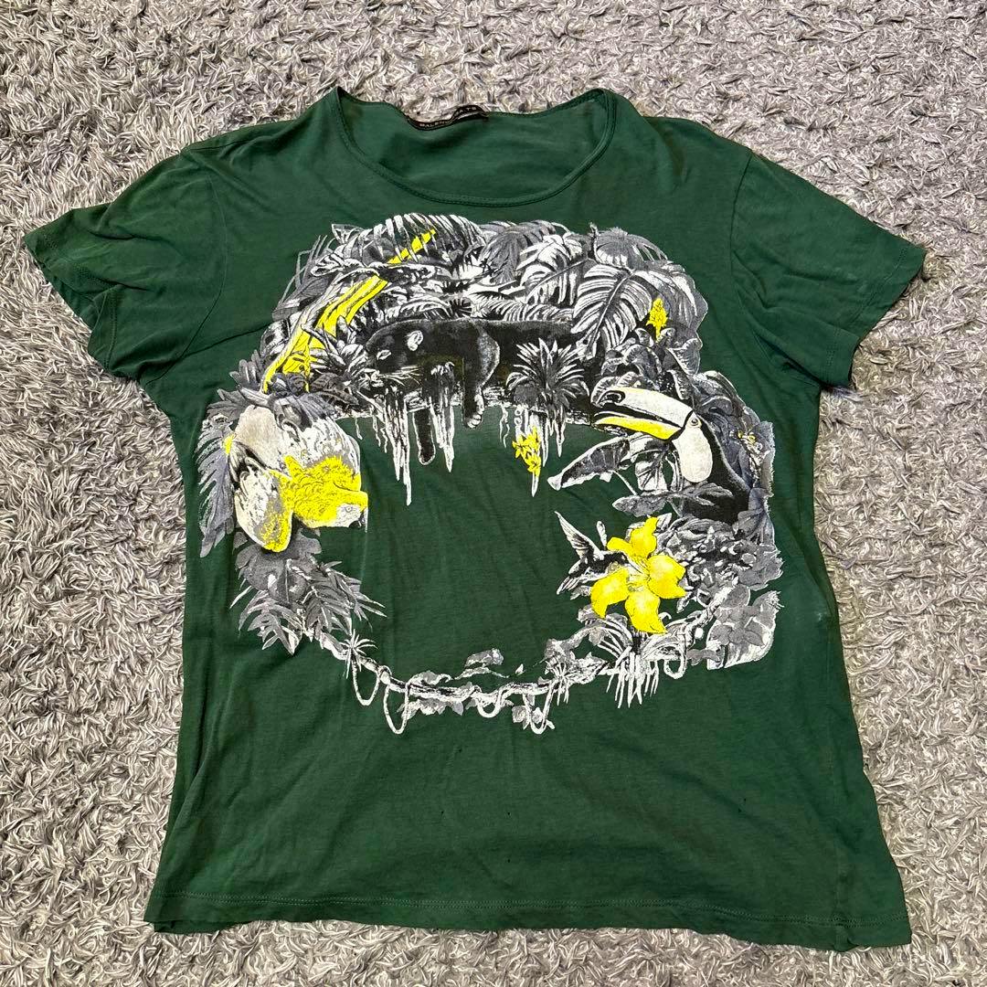 Flat-lay green Balenciaga men's cotton T-shirt showing a large animal and foliage print in white, black, and yellow on the front.
