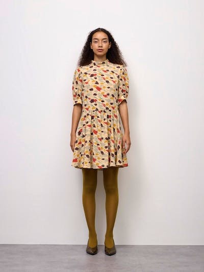 Front view of a model wearing the listed women's polyester dress with a beige base and multicolored print against a plain white background.