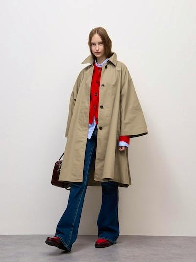 Model wearing the women's beige tent-line Balmacaan coat (super oversized fit) over layered clothing against a plain background.