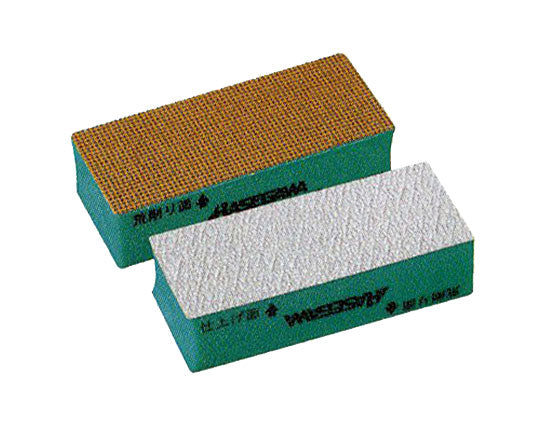 Two sandpaper-type shinai (bamboo sword) sharpening blocks with green sides and abrasive top surfaces.
