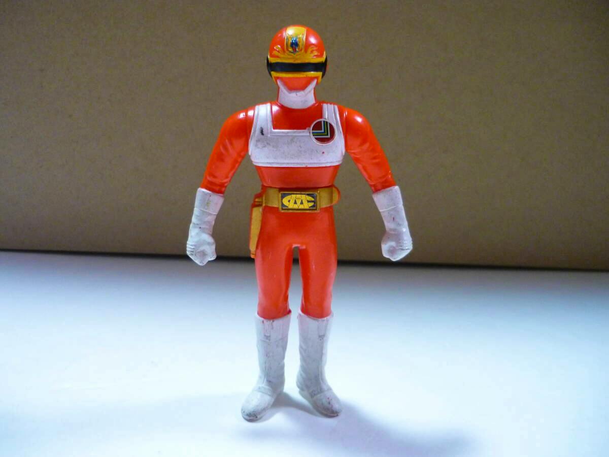 Front view of a red Change Dragon figure standing on a white surface with a brown background.